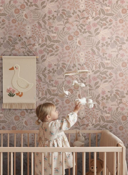 Vliestapete mit Blumen- und Vogelmuster in einem Kinderzimmer mit Gitterbett aus Holz und textilem Wandbehang.