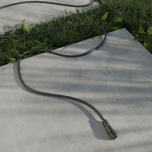 Außenkabel mit Stecker auf Steinplatten und Rasen im Garten.