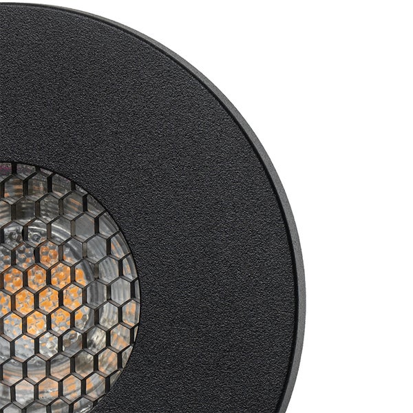 Nahaufnahme einer runden, mattschwarzen Außenleuchte mit strukturierter Oberfläche und Wabengitter vor dem LED-Leuchtmittel.