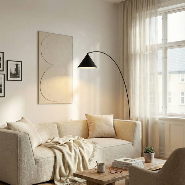 Helles Wohnzimmer mit beigem Stoffsofa, schwarzer Bogenstehlampe und hölzernem Couchtisch vor einem Fenster mit Vorhängen.