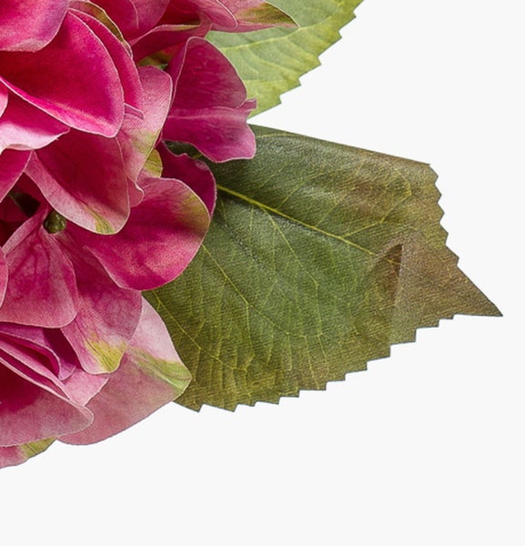 Nahaufnahme einer künstlichen rosafarbenen Hortensie mit gezackten grünen Blättern.