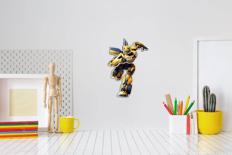 Wandtattoo von Transformers Bumblebee in Aktion an einer hellen Wand über einem organisierten Schreibtisch mit Gliederpuppe und Malutensilien.