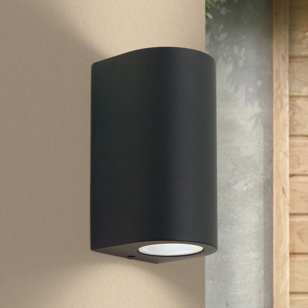 Moderne schwarze Außenwandleuchte in zylindrischer Form mit Lichtaustritt nach unten.