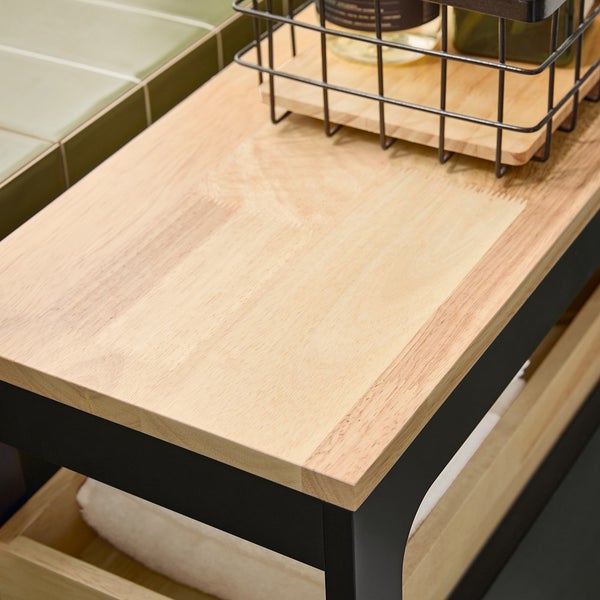 Detailansicht eines Waschtischunterschranks mit hölzerner Ablagefläche und schwarzem Metallrahmen