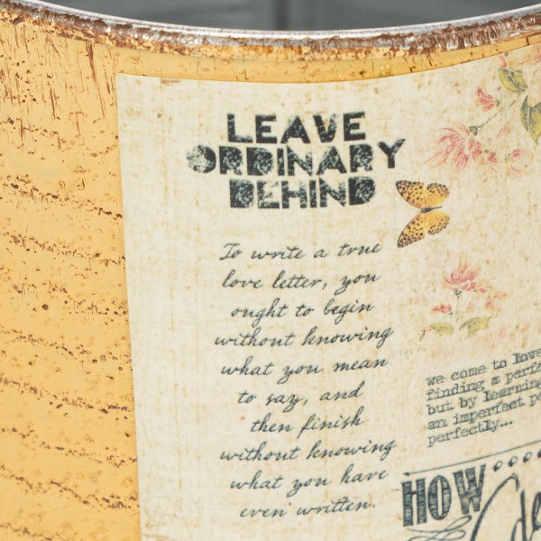 Detailansicht eines Dekotopfs mit Vintage Etikett, Schriftzug Leave Ordinary Behind und Blumenmustern.