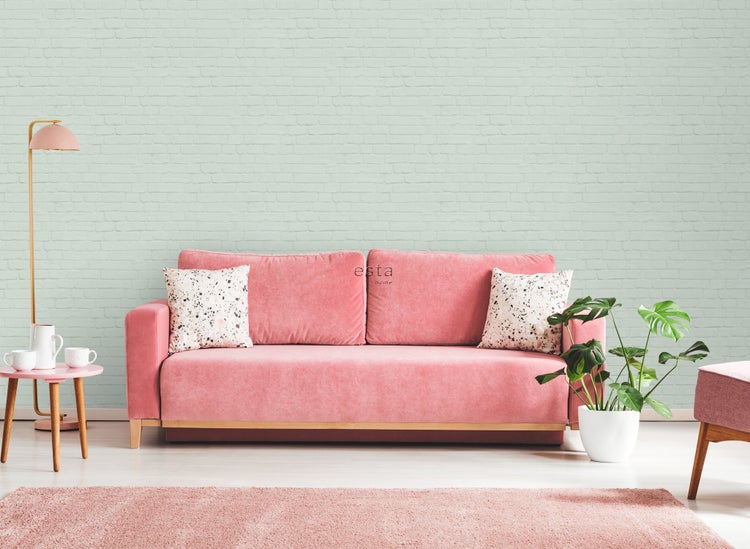 Wohnzimmer mit Sofa, Teppich, Beistelltisch, Stehlampe und Zimmerpflanze vor einer Ziegelwand