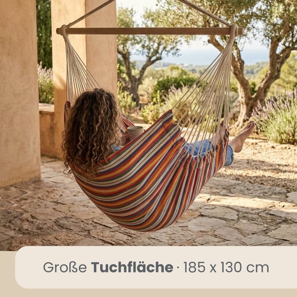 Mehrfarbig gestreifter Hängesessel mit Holzstab auf einer Terrasse, Tuchfläche 185 mal 130 Zentimeter.