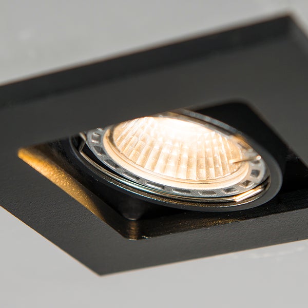 Quadratischer Einbaustrahler aus Metall in Schwarz, schwenkbarer Spot mit eingeschaltetem Leuchtmittel.