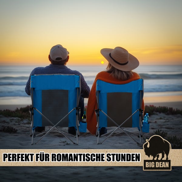 Ein Paar sitzt in blauen Campingstühlen am Strand bei Sonnenuntergang