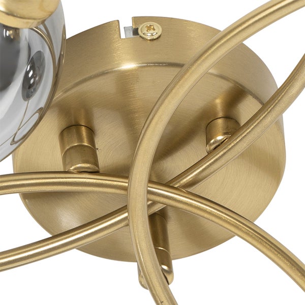 Detailansicht einer Deckenleuchte mit goldfarbenem Metallgestell und transparenten Glaskugeln.