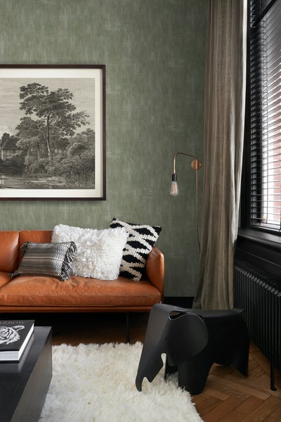 Wohnzimmer mit braunem Ledersofa, Kissen und dekorativer Elefantenhocker