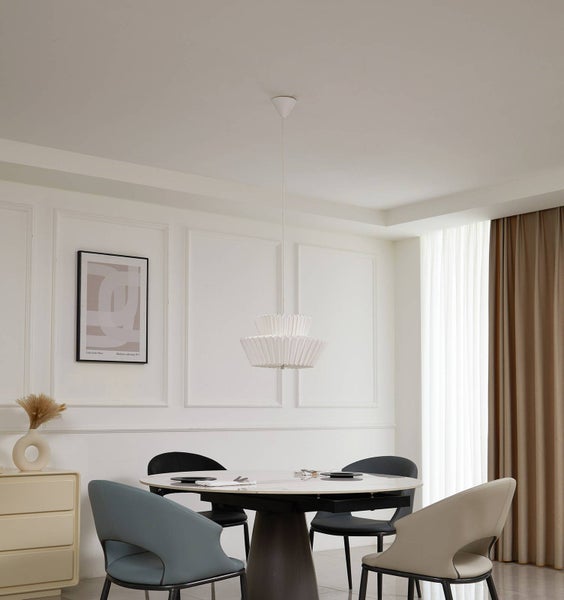Moderne zweistufige Pendelleuchte mit plissiertem Lampenschirm über einem runden Esstisch in einem hellen, minimalistischen Esszimmer.
