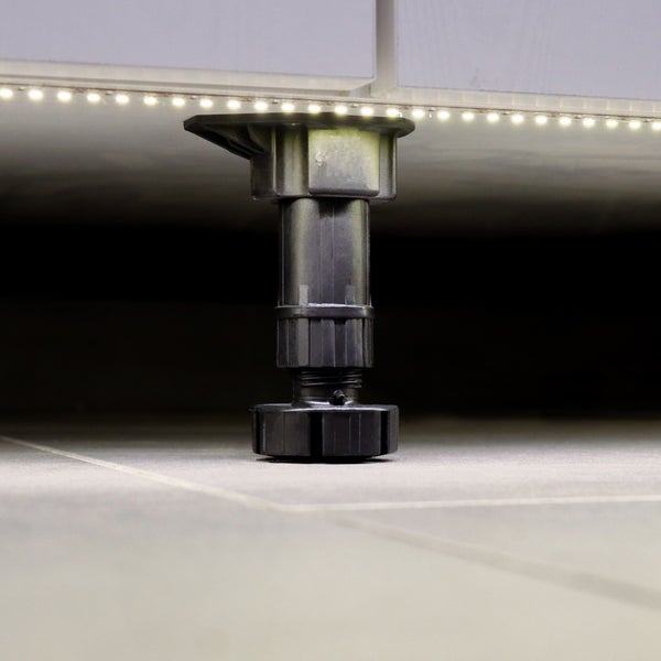 Verstellbarer Sockelfuß für Küchenmöbel zur Höhenanpassung unter einem Schrank mit integrierter LED Beleuchtung.
