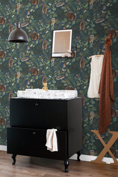 Kinderzimmer mit schwarzer Kommode, Wickelauflage und Tapete mit Tiermotiven.