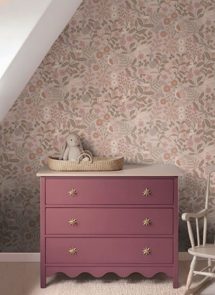 Blumentapete mit Vögeln und Schmetterlingen hinter einer Kommode mit goldenen Sternengriffen in einem Kinderzimmer.