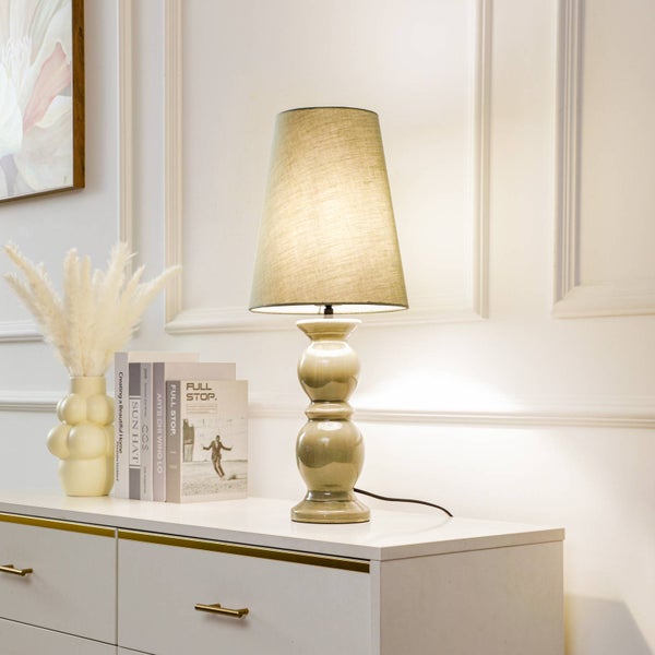 Dekorative Tischleuchte mit Lampenschirm aus Stoff auf einer Kommode