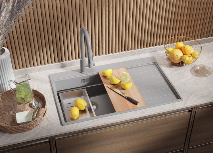 Küchenszene mit Spüle, Armatur, Schneidebrett mit Zitrone und Messer, sowie Accessoires auf einer Küchentheke.