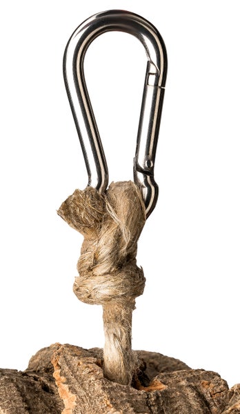 Karabinerhaken aus Metall an einem Naturseil, das an einem Stück Korkrinde befestigt ist.