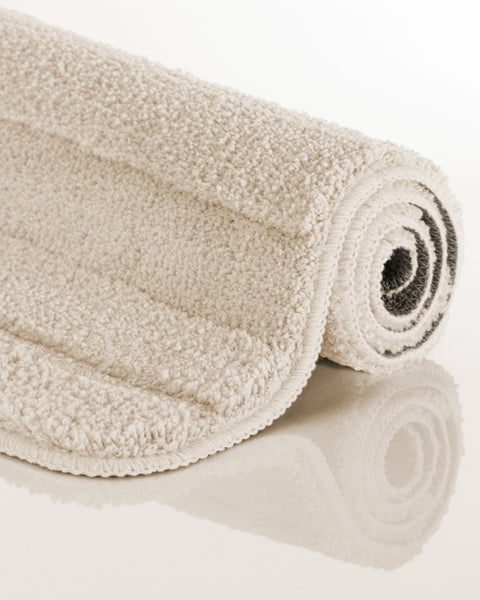 Aufgerollte beige Badematte mit weicher, strukturierter Plüsch-Oberfläche.