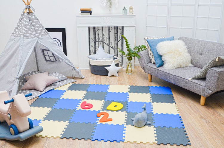 Helles Kinderzimmer mit Puzzle-Spielmatte, Tipi-Zelt, Schaukelpferd und kleinem Sofa auf Holzboden.