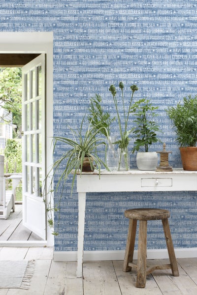 Dekoratives Interieur mit Pflanzen auf einem Tisch vor einer gemusterten Wand