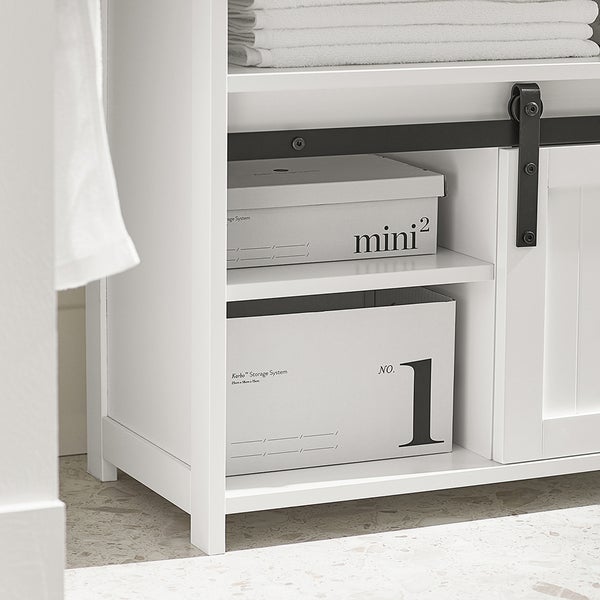 Detailaufnahme eines weißen Badezimmerschranks mit Aufbewahrungsboxen und Handtüchern.