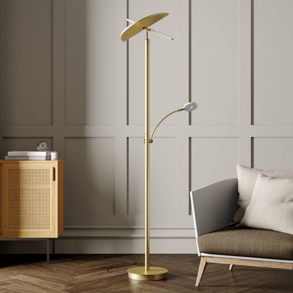 Moderne Stehleuchte in Messing-Optik mit Deckenfluter und Lesearm in einem hellen Wohnzimmer mit Parkettboden und Sessel.