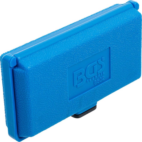 Kugel- und kegelförmig geschnittene Buchsbäume in großen schwarzen Kunststofftöpfen auf einer Kiesfläche vor einem Gewächshaus.