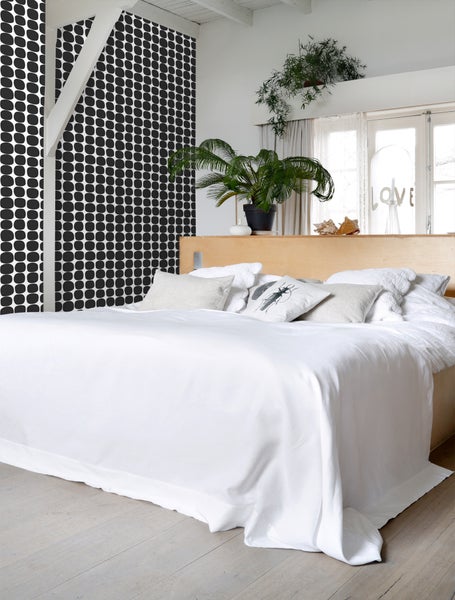 Schlafzimmer mit Bett, Kissen und Tapete mit Punktmuster