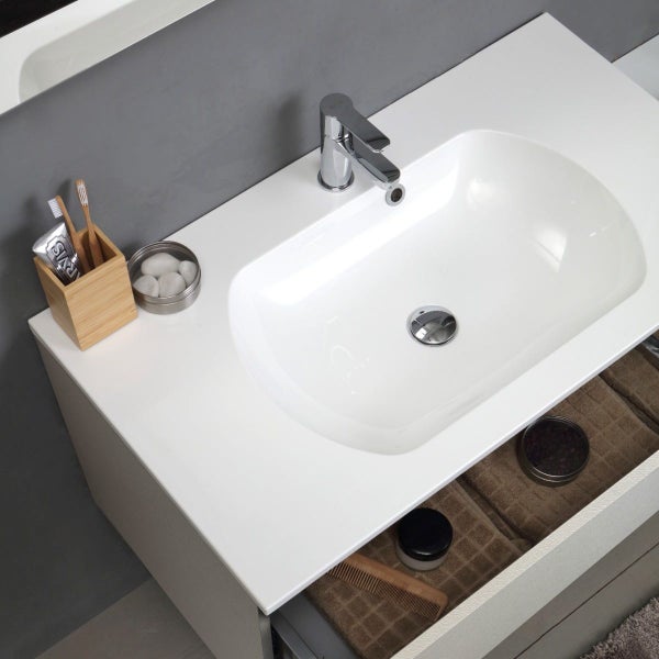 Waschbecken mit Armatur, Zahnbürste, Zahnpasta, Handtüchern und Kosmetika auf einem Waschtischunterschrank.