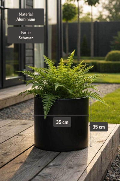 Schwarzer runder Pflanzkübel aus Aluminium mit Farn, Maße 35 mal 35 Zentimeter, auf einer Holzterrasse im hellen Garten.