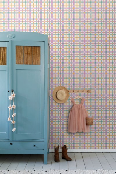 Karierte Tapete mit fliederfarbenen, grünen und gelben Streifen in einem hellen Zimmer mit blauem Schrank, rosa Kleid und Holzboden.