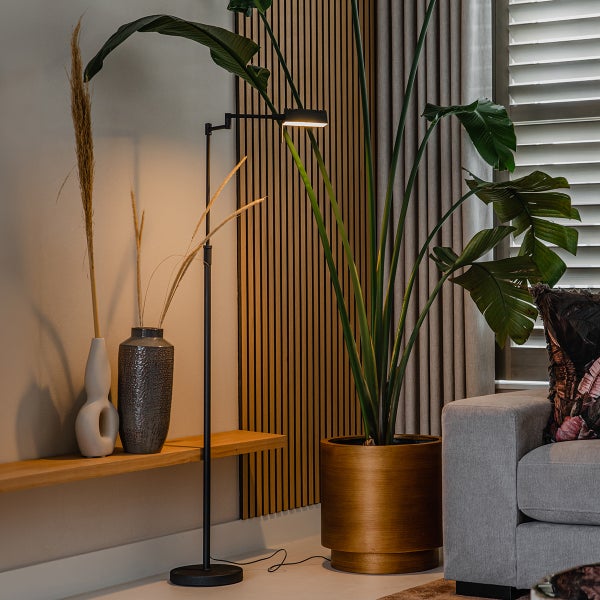 Wohnzimmer mit Stehlampe, Topfpflanze und Dekorationsvasen auf einem Holzregal.