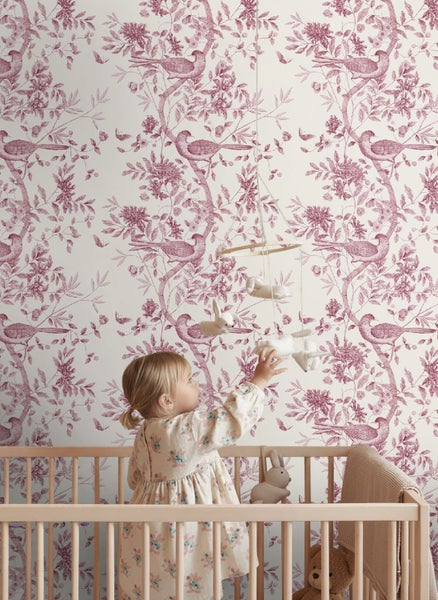 Vliestapete mit Vogel- und Blumenmuster in einem Kinderzimmer hinter einem Gitterbett mit einem Kleinkind.