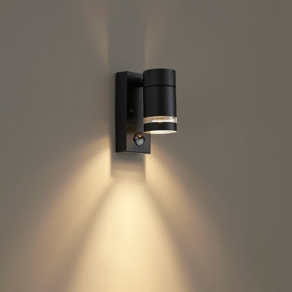 Schwarze Außenwandleuchte mit Bewegungsmelder, zylindrischem Lampenkopf und Lichtkegel nach unten.