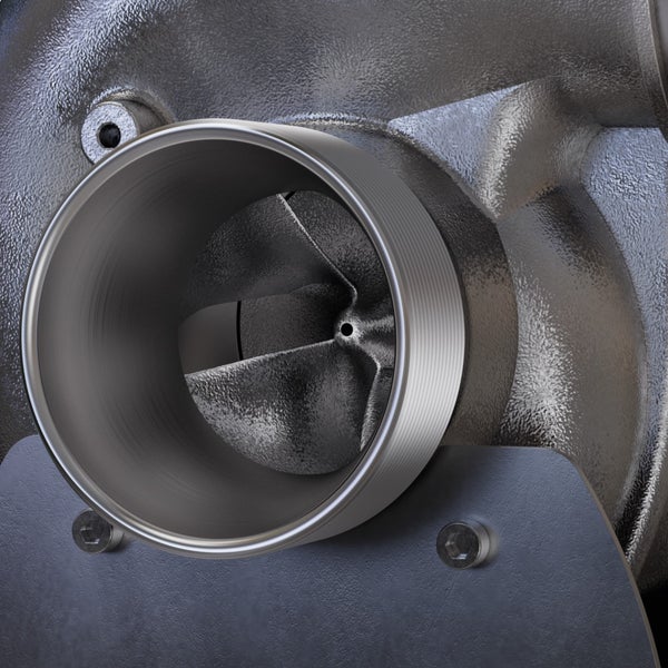 Nahaufnahme eines metallischen Turbolader-Einlasses mit inneren Schaufelrädern und Gehäuse mit Befestigungsschrauben.