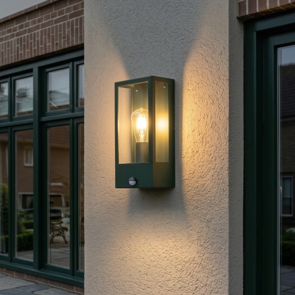 Moderne rechteckige Außenwandleuchte mit Bewegungsmelder an einer Fassade, warmes Licht eines Filament-Leuchtmittels erhellt die Umgebung.
