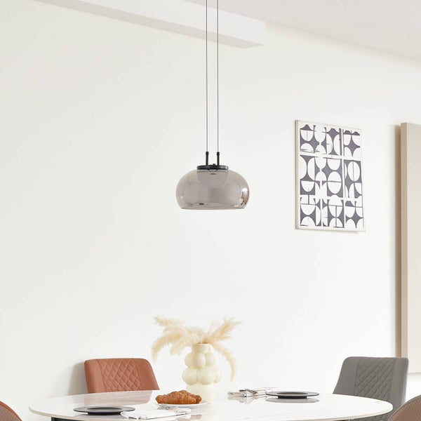 Moderne Pendelleuchte mit rauchigem Glasschirm über einem Esstisch in einem hellen, minimalistischen Esszimmer mit geometrischer Wandkunst.