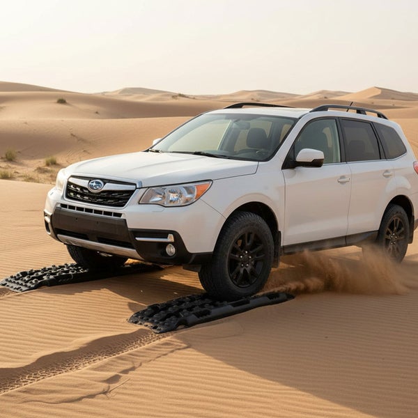 Weißes Auto fährt mit Anfahrhilfe durch Sand