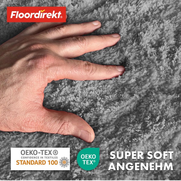 Detailansicht eines grauen, superweichen Teppichs mit einer Hand, die das Material berührt, mit Floor direkt Logo und OEKO-TEX Siegel