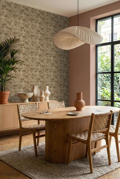 Esszimmer mit Blumentapete, Holzesstisch, geflochtenen Stühlen und einer modernen Pendelleuchte in natürlichem Wohnambiente.
