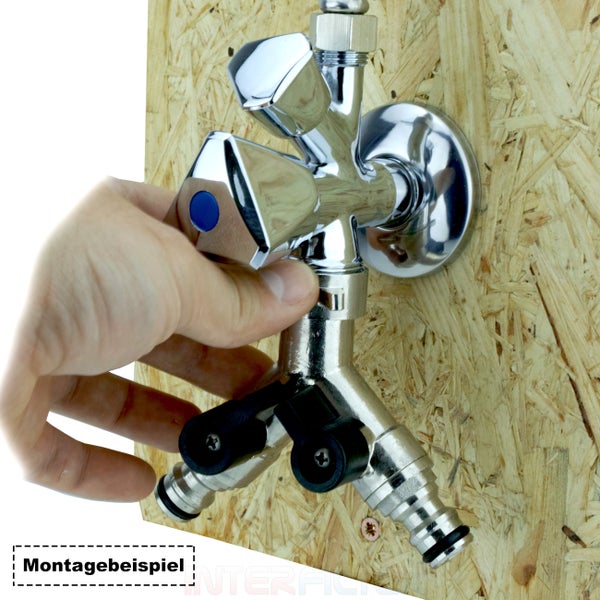 Ein metallener Doppel Auslaufhahn mit zwei Anschlüssen montiert an einer Holzplatte wird von einer Hand bedient als Montagebeispiel.