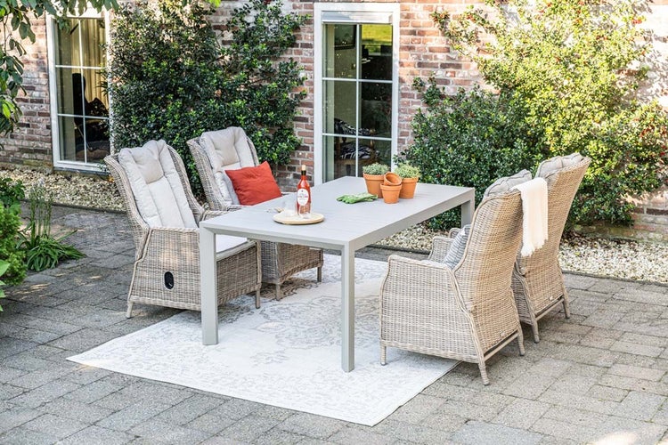 Modernes Gartenmöbel-Set aus Polyrattan mit einem rechteckigen Tisch und vier Hochlehner-Sesseln mit hellen Auflagen auf einer gepflasterten Terrasse.