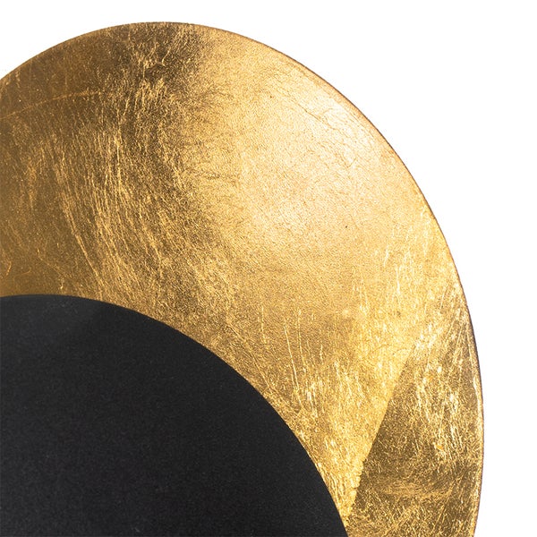 Detailaufnahme einer runden Wandleuchte mit goldfarbener Oberfläche und schwarzem Hintergrund