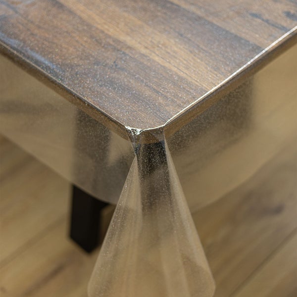 Transparente Tischdecke mit Glitzereffekt auf einem Holztisch.