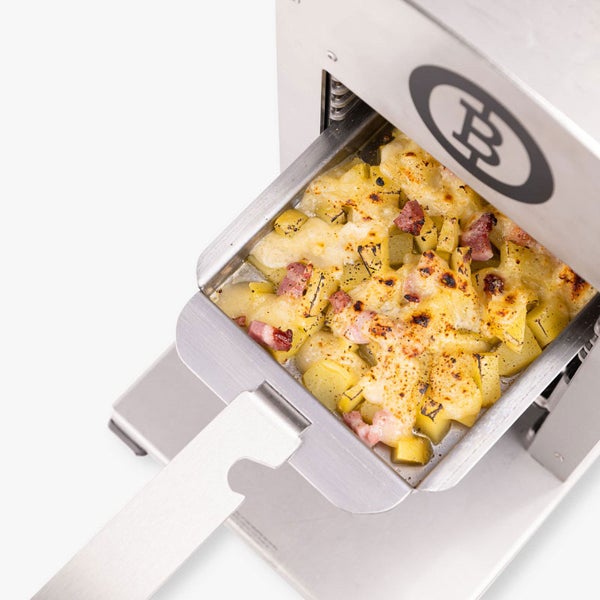 Oberhitzegrill aus Edelstahl mit einer Schale überbackener Kartoffeln mit Käse und Speck. Beefer Logo.