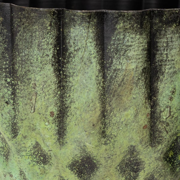 Detailaufnahme einer gewellten Metalloberfläche mit einer grünen Patina.