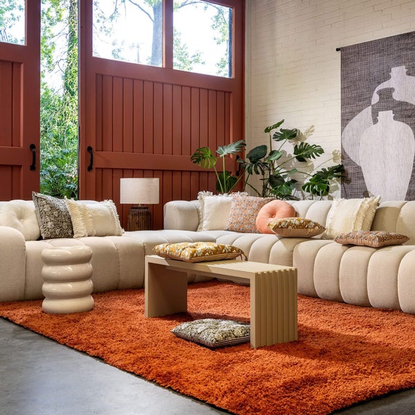 Wohnzimmer mit modularem Sofa, Bank und orangem Teppich