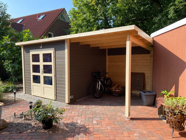 Modernes Gartenhaus aus Holz in Anthrazit mit Flachdach, Doppeltür und integriertem Schleppdach auf einer gepflasterten Terrasse.