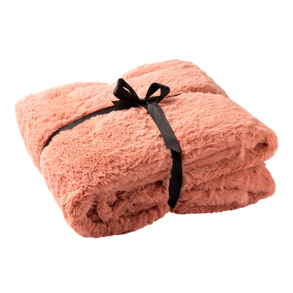 Zusammengelegte Kuscheldecke aus Kunstfell in Lachsrosa, mit schwarzem Band gebunden.